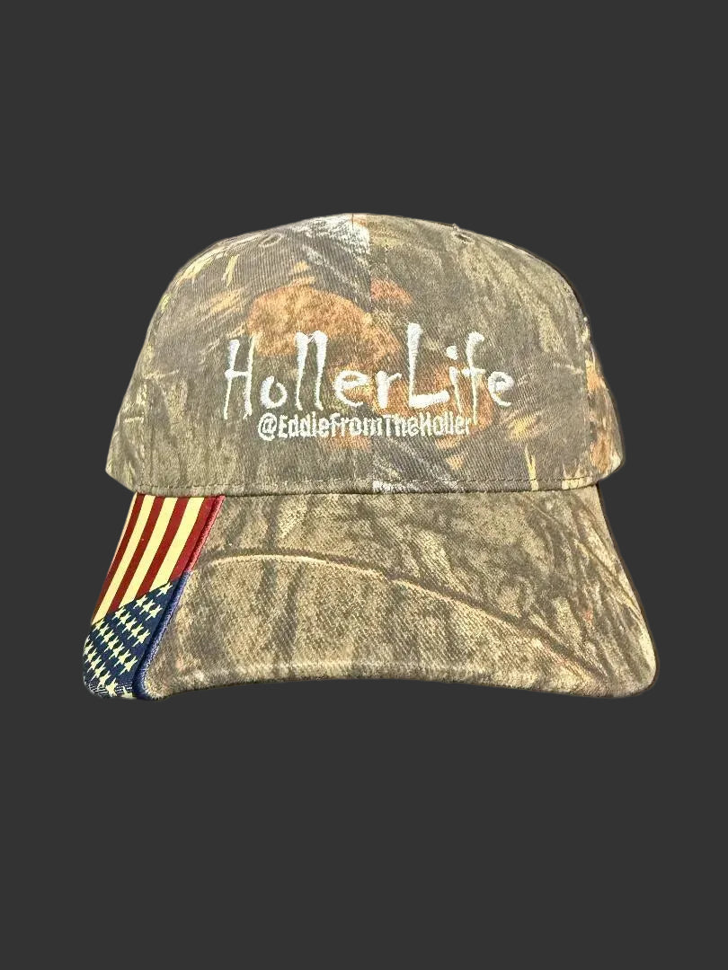 Camouflage cap featuring 'HollerLife' embroidered, with an American flag on the bill, a solid back, and an adjustable strap.
